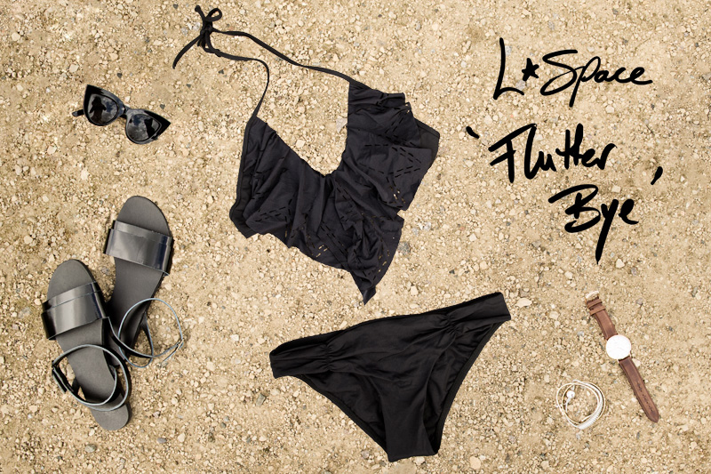FAIIINT Bikini shopping round up, L Space Flutter Bye frill drape cut out laser cut black bikini, with ASOS Sandals, ASOS Cateye sunglasses, Daniel Wellington watch, Whistles & Links of London Bracelets. All black swimwear styling.