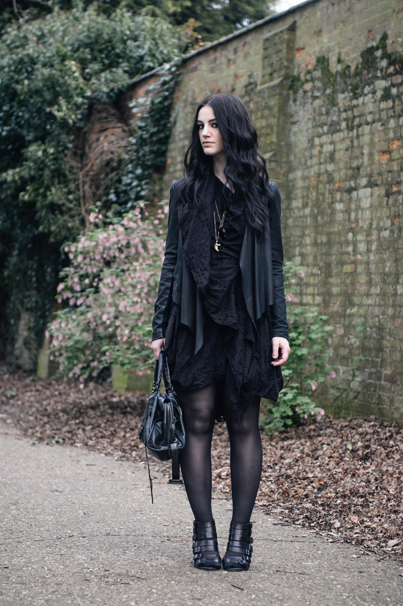 Fashion blogger Stephanie of FAIIINT wearing Allsaints draped embroidery anglaise dress, Barneys Originals leather jacket, Kurt Geiger buckled wedges, Balenciaga city bag, claw & obsidian arrowhead necklaces. All black outfit street style.