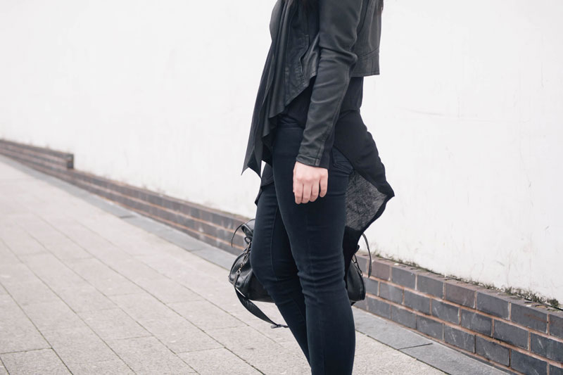 Fashion blogger Stephanie of FAIIINT wearing Barneys Originals draped leather jacket, Topshop skinny jeans & asymmetric top, Balenciaga city bag. Casual all black street style outfit.