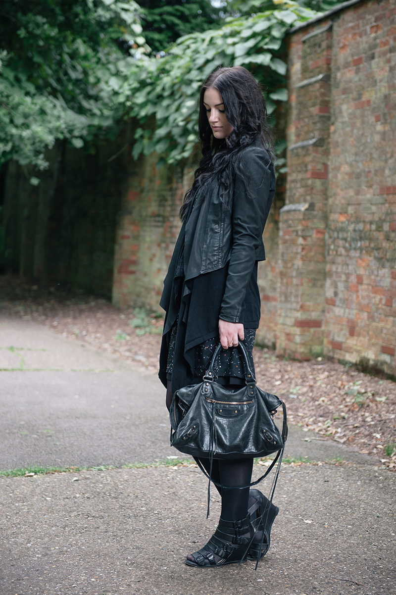 Fashion blogger Stephanie of FAIIINT wearing Barneys Originals draped leather jacket, ASOS cardigan, Yumi constellation print dress, Kurt Geiger buckle wedges, Balenciaga city bag. All black street style outfit.