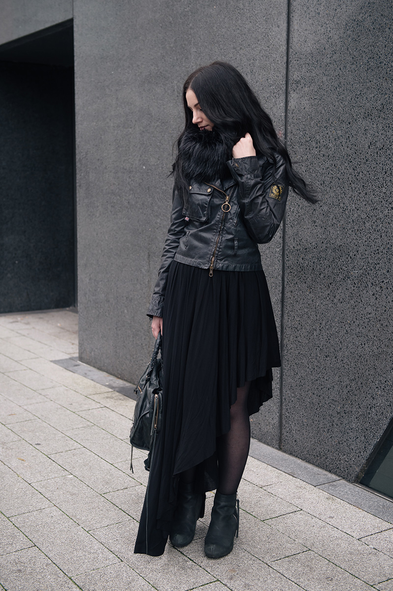 Fashion blogger Stephanie of FAIIINT wearing FAIIINT faux fur snood, Belstaff Sammy Miller waxed jacket, H&M asymmetric jersey maxi skirt, Kurt Geiger wedge boots, Balenciaga city bag. All black street style outfit.