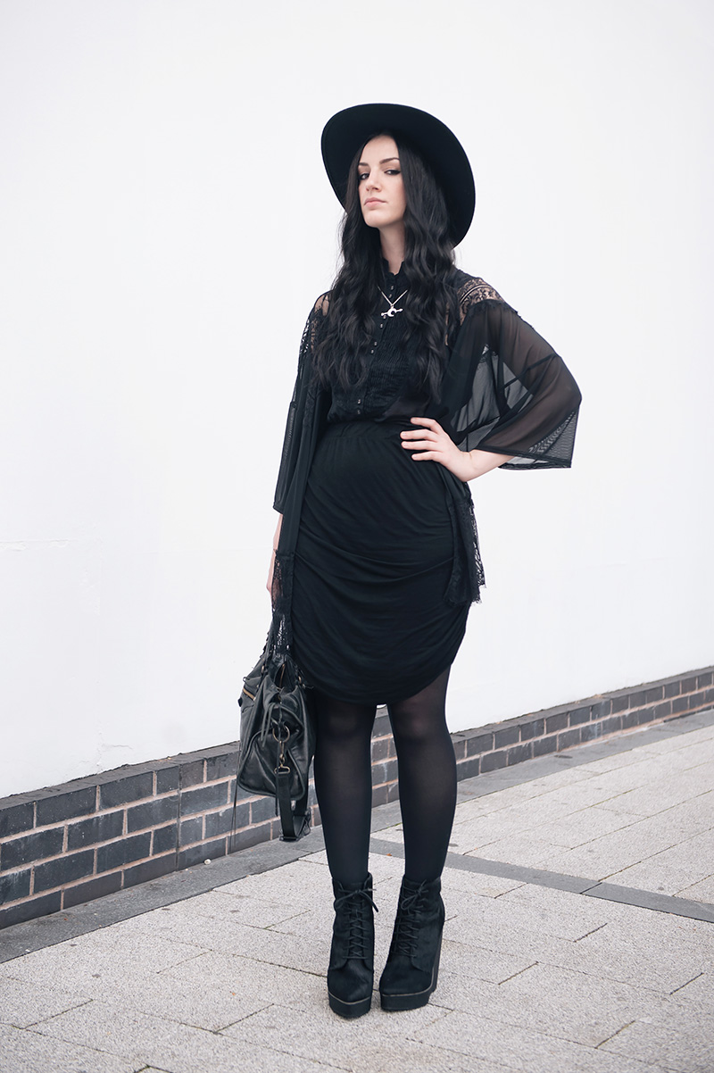 Fashion blogger Stephanie Brown of FAIIINT wearing Catarzi fedora, Pins & Needles at Urban Outfitters lace kimono, AllSaints Shirt, Religion draped skirt, Bloody Mary Metal Luna Tribe Luna Love necklace, Kurt Geiger ponyhair wedge boots, Balenciaga city. Dark street style, all black witchy outfit.