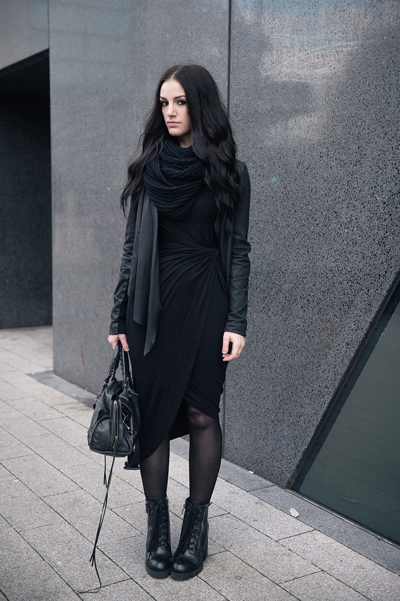 Fashion blogger Stephanie of FAIIINT wearing ASOS Knitted snood, Barneys Originals draped leather jacket, H&M knot twist dress, Giles Deacon Libertine thorn gold ring, Ash Poker lace up boots, Balenciaga city bag. All black everything street style outfit.