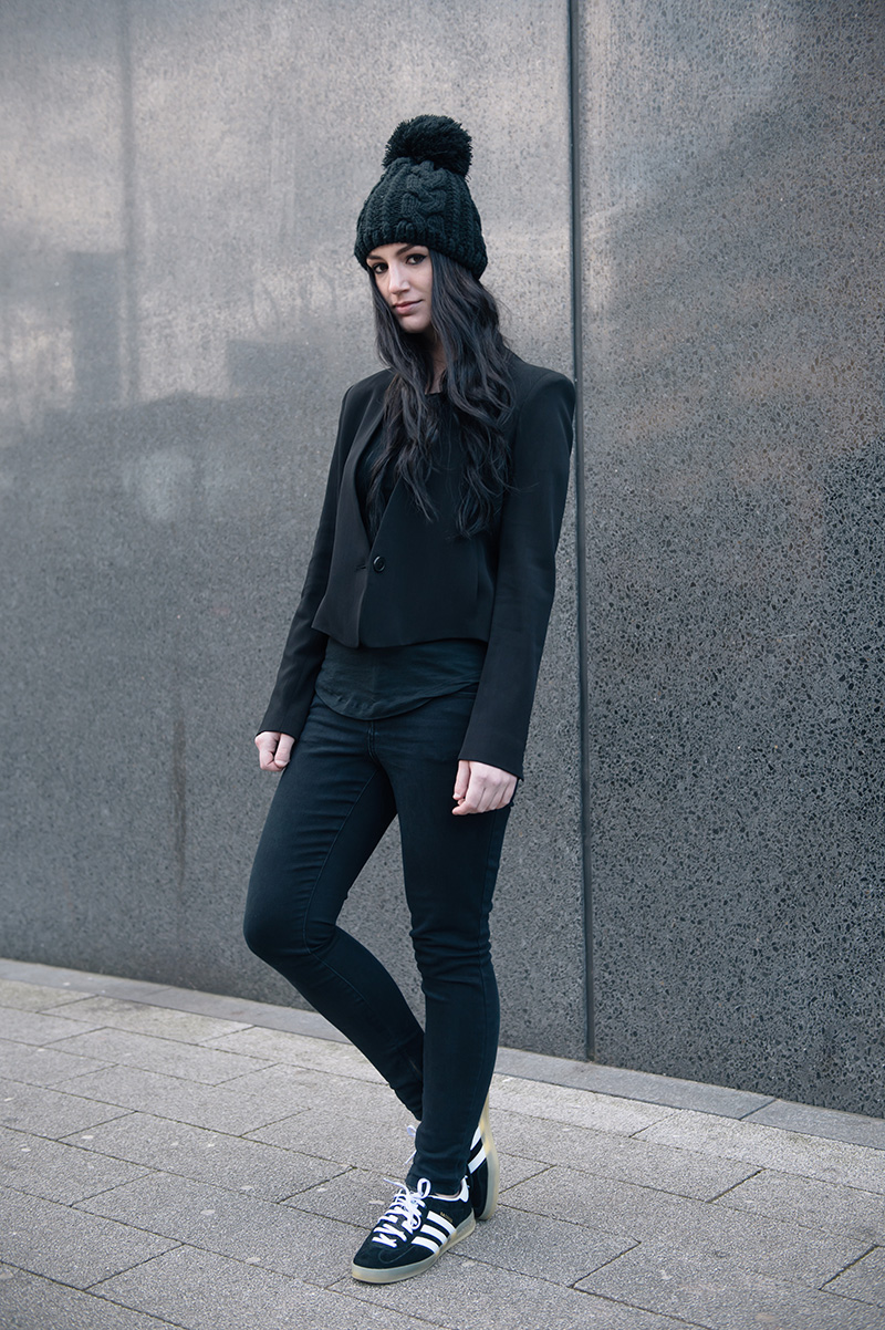 Fashion blogger Stephanie of FAIIINT wearing OASAP pom pom beanie, Theyskens' Theory Cropped Jacket, ASOS Tank Top, Topshop Skinny Jeans, Adidas Gazelle Indoor black trainers. Casual street style all black outfit.