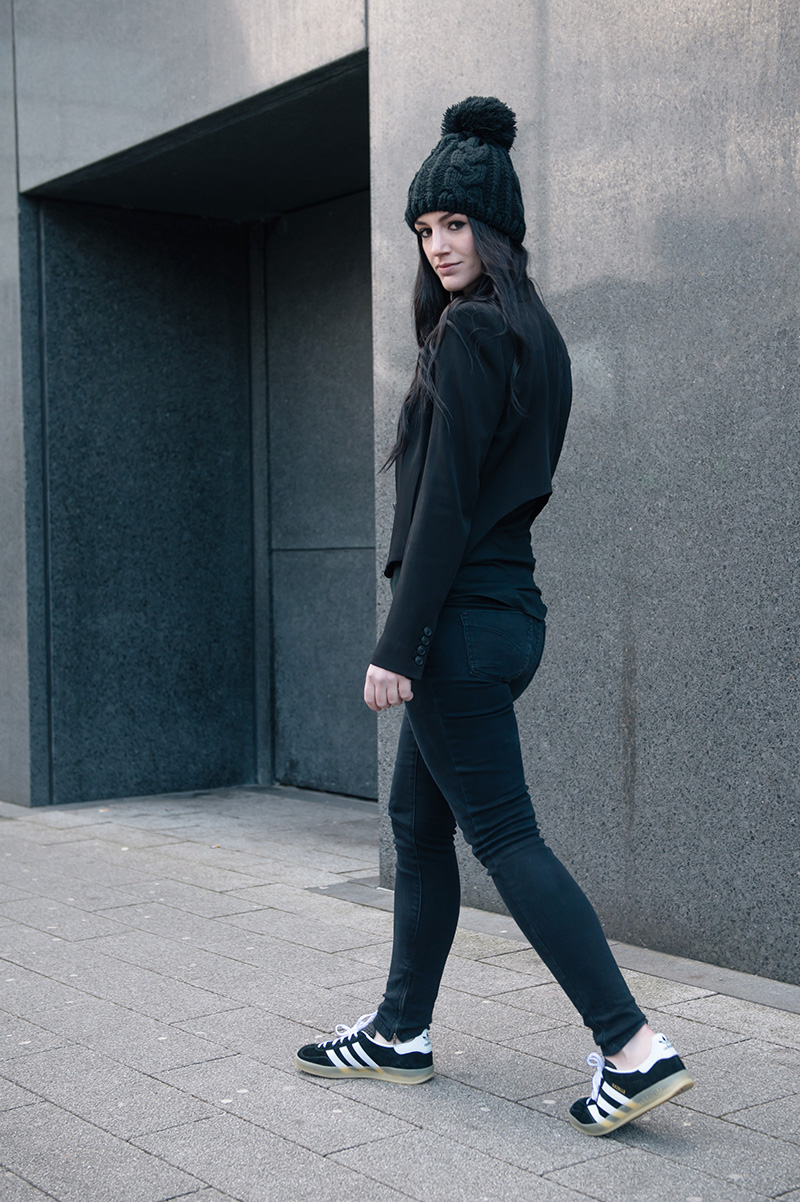 Fashion blogger Stephanie of FAIIINT wearing OASAP pom pom beanie, Theyskens' Theory Cropped Jacket, ASOS Tank Top, Topshop Skinny Jeans, Adidas Gazelle Indoor black trainers. Casual street style all black outfit.