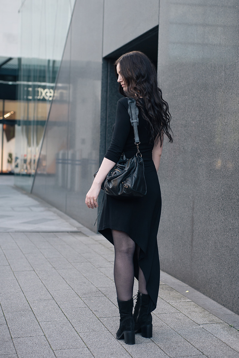 Fashion blogger Stephanie of FAIIINT wearing FAIIINT asymmetric slash one sleeve jersey dress, Kurt Geiger lace up Saturn suede boots, Balenciaga City bag, A Weathered Penny brass rings. All black everything street style summer goth outfit.