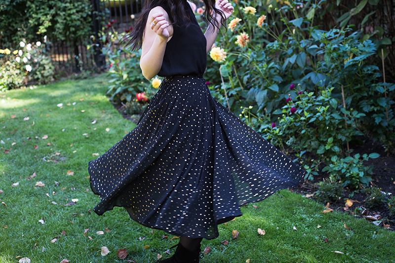 Fashion blogger Stephanie of FAIIINT wearing Yumi sleeveless blouse, Yumi gold spot polka dot pleated black chiffon midi skirt. Twirling around, outfit details.