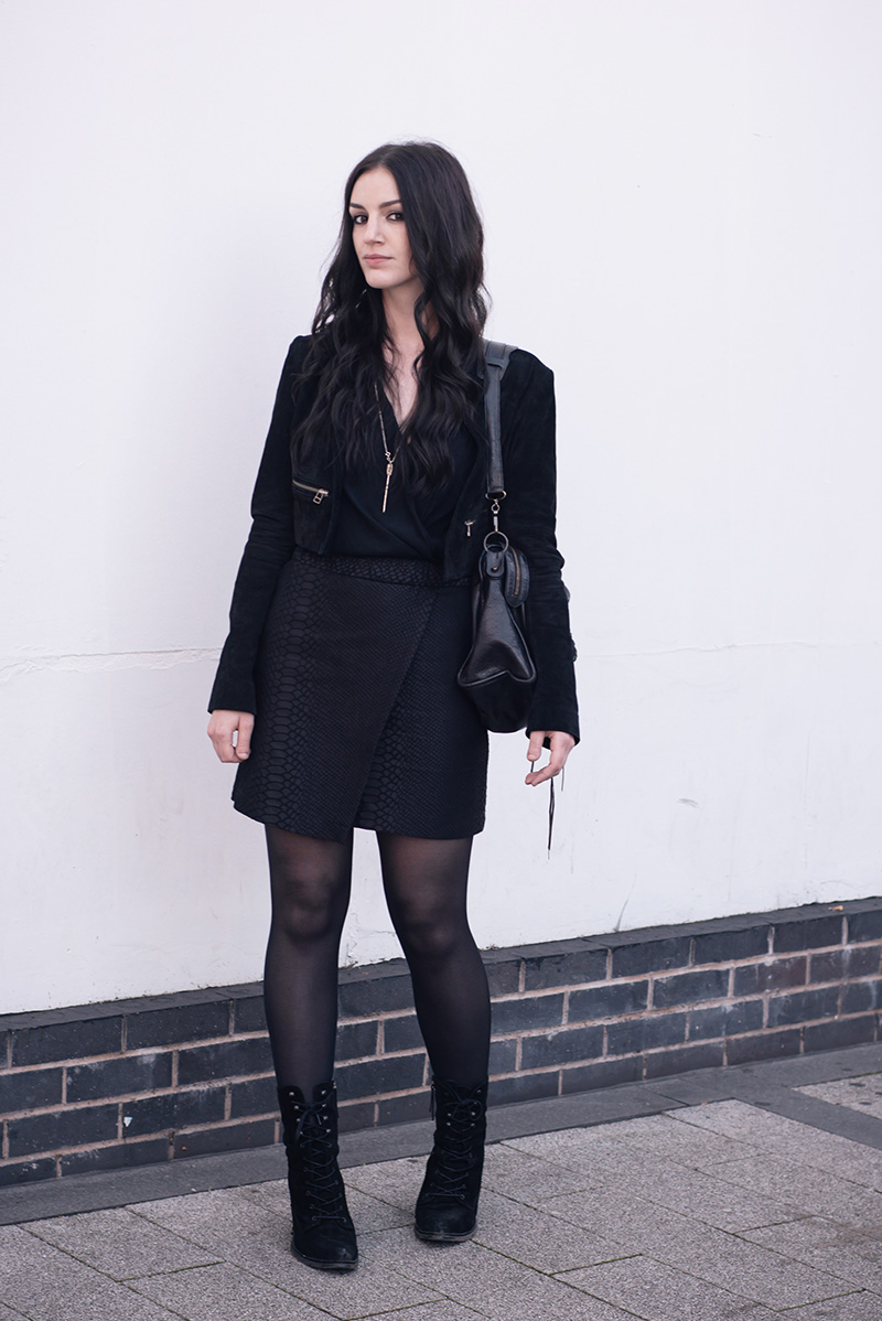 Fashion blogger Stephanie of FAIIINT wearing Topshop suede cropped jacket and snake texture wrap skirt, River Island Draped Blouse, Bloody Mary Metal Lovehunters Arrow Silver Necklace, Kurt Geiger Saturn Boots, Balenciaga City Bag. All black everything dark street style outfit.
