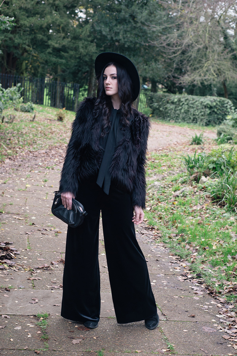 Fashion blogger Stephanie of FAIIINT wearing Catarzi fedora, H&M Faux fur jacket, F&F chiffon and velvet jumpsuit, Kurt Geiger boots, Betty Jackson Black bag. All black everything dark style 70s outfit.