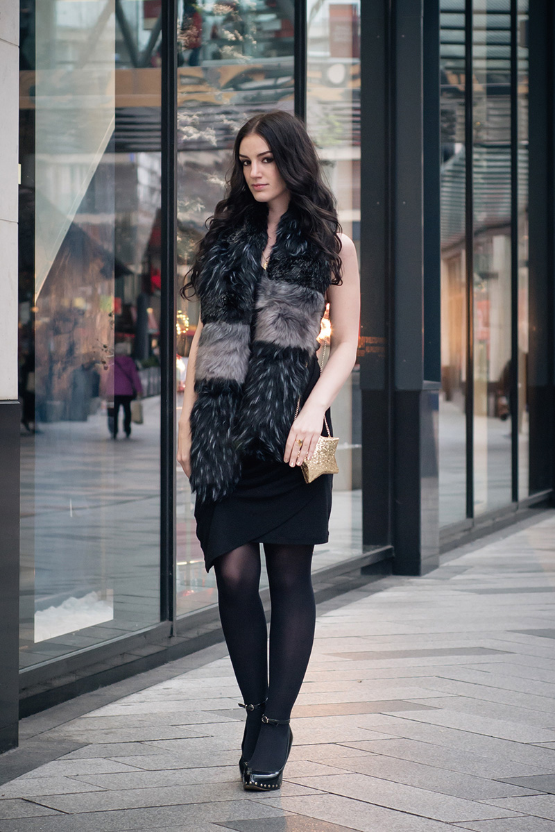 Fashion blogger Stephanie of FAIIINT wearing New Look black and grey faux fur stole and gold glitter star box clutch bag, Selected Femme dress, Aldo studded wedges. All black everything, festive Christmas party outfit street style.