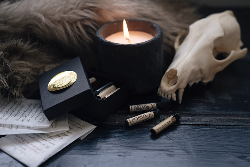 FAIIINT x For Strange Women natural botanical perfume oil sample vials coyote, fossil and astral projection in still life with coyote skull, faux fur and candle.