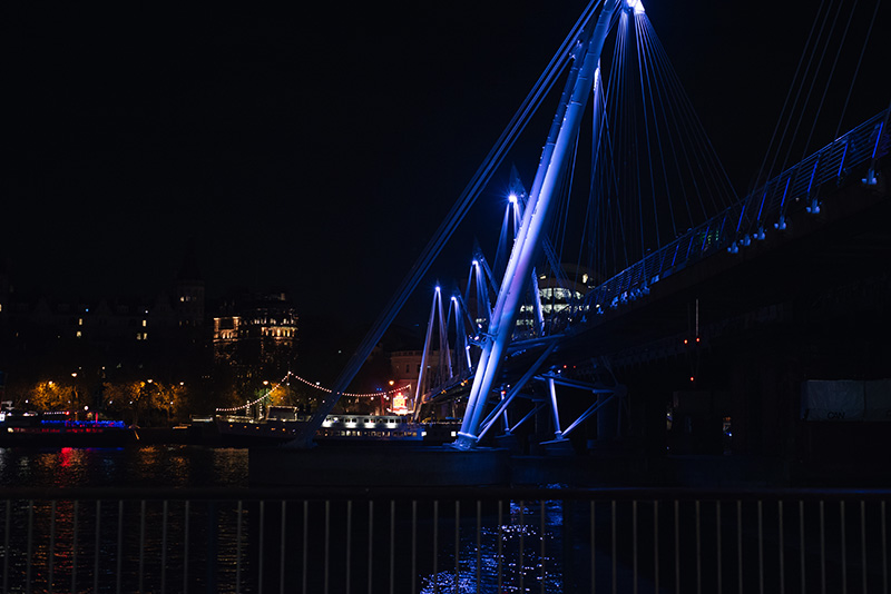 FAIIINT London Southbank bridge and river Thames lit up at night.