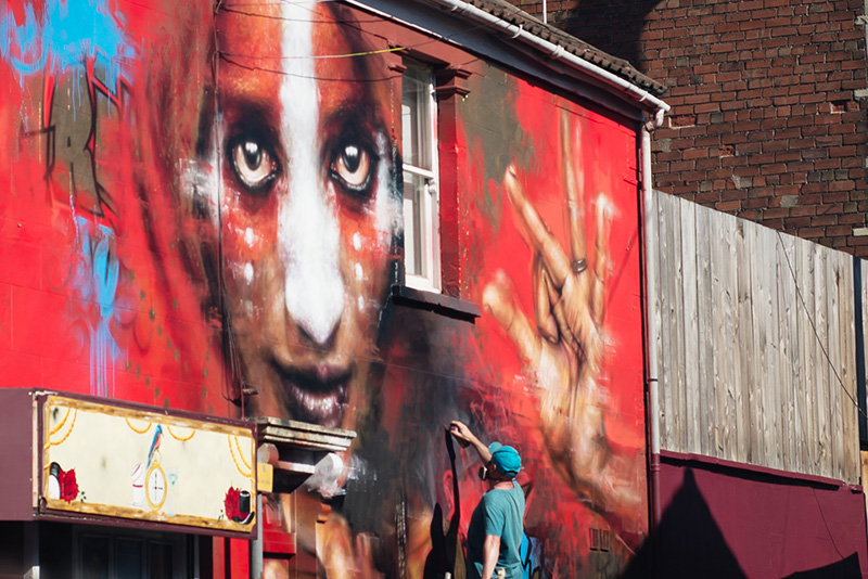 Bristol Upfest street art festival. Artist painting large mural on building.