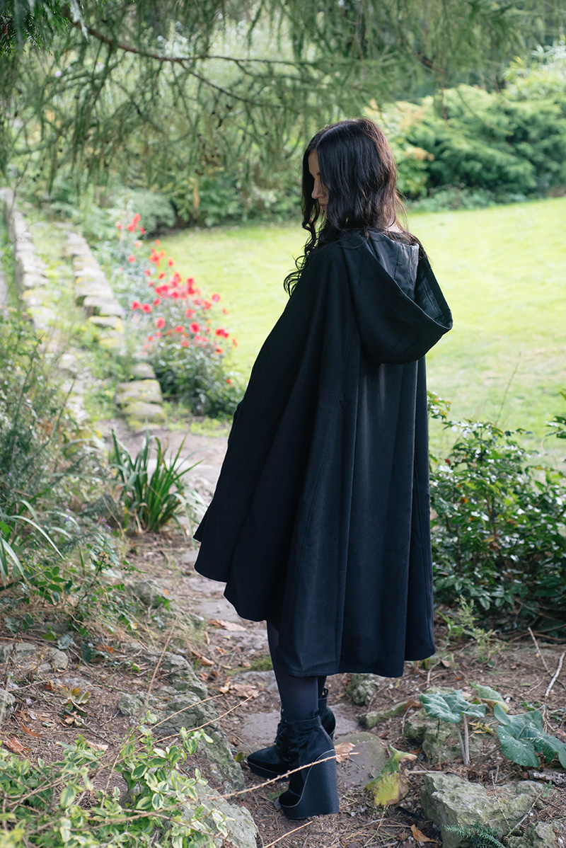 Fashion blogger Stephanie of FAIIINT wearing Necessary Evil Morrigan wool cape, Black.co.uk cashmere wrist warmers, The Rogue + The Wolf Occult ring, Kurt Geiger Solar ponyhair wedge lace up boots. All black gothic autumn outfit.