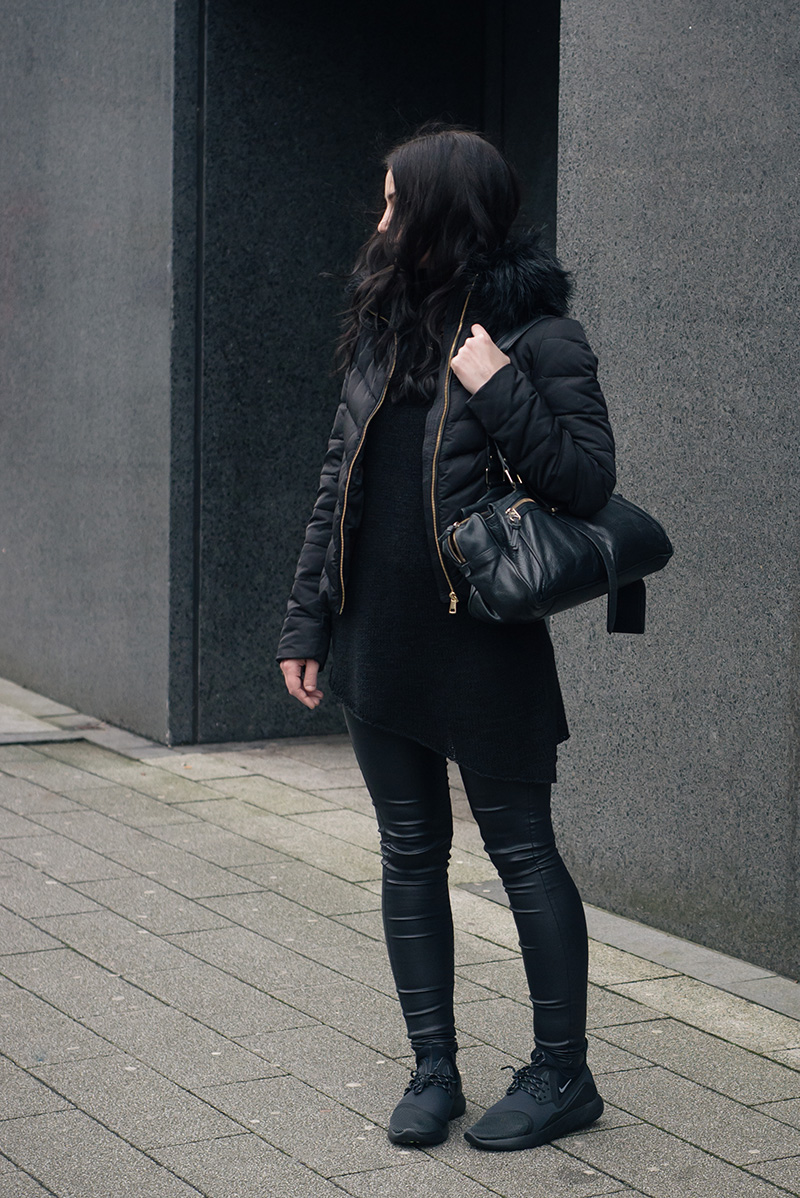 Fashion blogger Stephanie of FAIIINT wearing H&M quilted padded down jacket with faux fur collar, H&M asymmetric jumper, New Look coated skinny jeans, Nike black LunarCharge trainers, Mulberry Mabel bag. All black winter street style outfit.