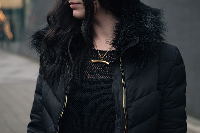 Fashion blogger Stephanie of FAIIINT wearing H&M quilted padded down jacket with faux fur collar, Sara Gunn gold bone necklace. All black outfit details.