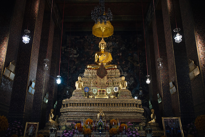 Temples of Bangkok Thailand, Wat Pho gold buddha statue with offerings inside central shrine.