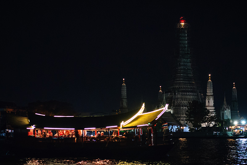 Bangkok Thailand view of Wat Arun and tourist boat on the Chao Phraya River.