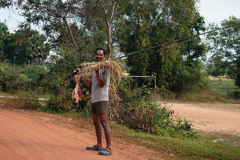 Motorbiking through the Siem Reap countryside in Cambodia. Local fisherman on the road.