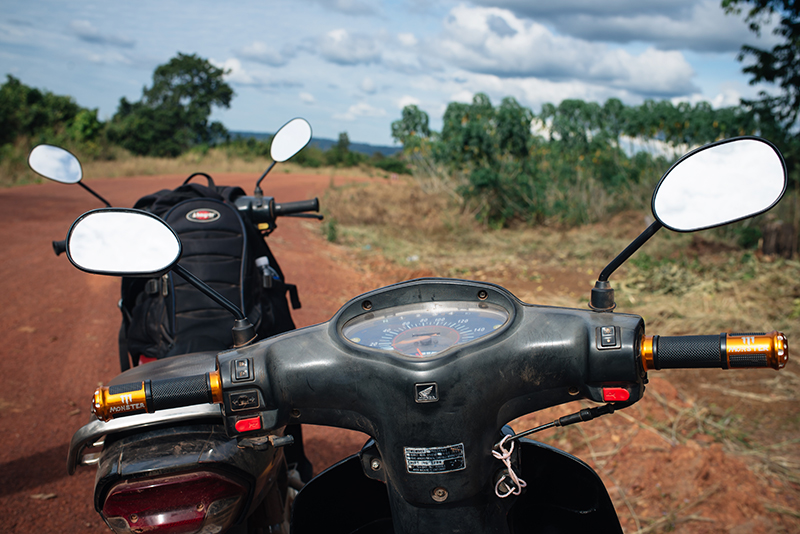Motorbiking throught the Siem Reap countryside in Cambodia on a Honda Dream. Dusty red orange sand roads.