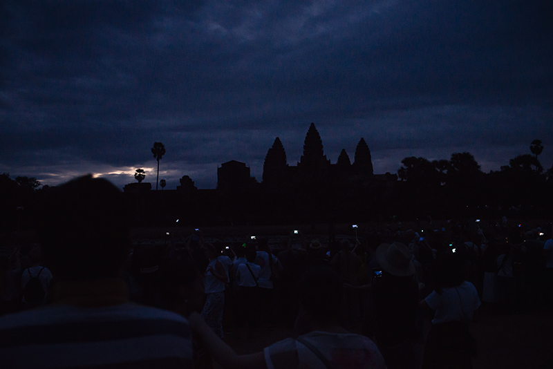 Crowd with mobile phones in the dark waiting for sunrise at Angkor Wat temple complex Siem Reap Cambodia.