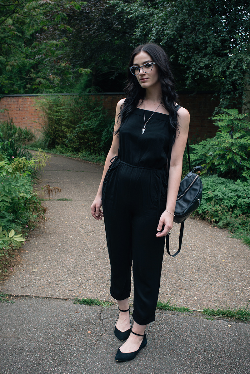 Fashion blogger Stephanie of FAIIINT wearing Warehouse jumpsuit, IOLLA Muir smoke tortoise frames glasses, Topshop pointed flats, Toilworn arrowhead necklace, New Look backpack. All black everything, casual street style outfit.