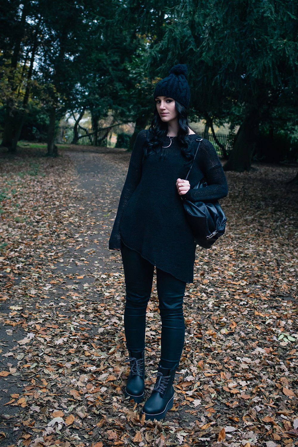 Fashion blogger Stephanie of FAIIINT wearing pom pom beanie hat, H&M black asymmetric knit jumper, coated skinny jeans, Dos61 high rubber boots, Topshop backpack. All black autumn outfit.