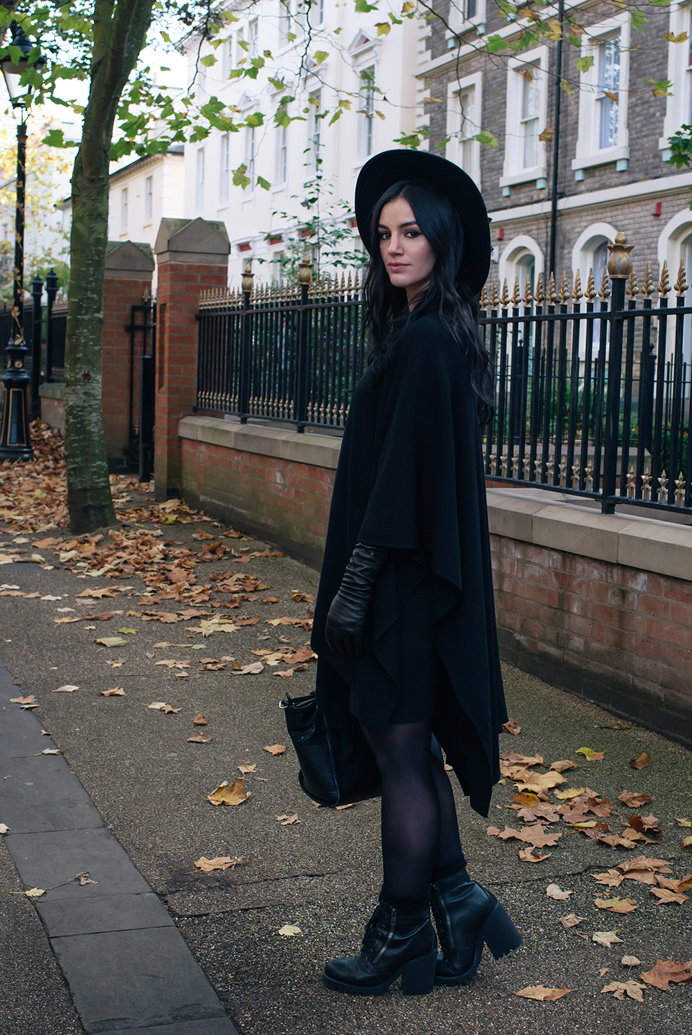 Fashion blogger Stephanie of FAIIINT wearing ASOS cape, H&M wide brim fedora, Black elbow high leather gloves, ASH poker lace up boots. Gothic style all black autumn outfit.