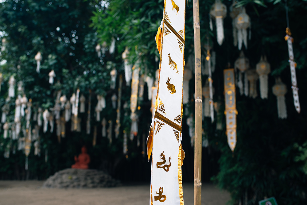 Wat Phan Tao flags and Buddha statue garden Chiang Mai Thailand.