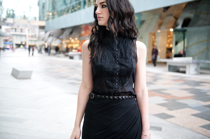 Fashion blogger Stephanie of FAIIINT wearing AllSaints Sleeveless Shirt, River Island Draped Asymmetric Skirt, Skin by Finsk Wedge Sandals, Topshop Studded Belt, ASOS Spiked Bangle, Balenciaga City bag. All black, dark, gothic, street style.