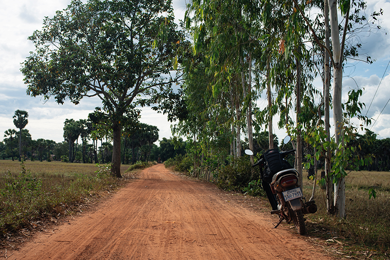 Motorbiking through the Siem Reap countryside in Cambodia on a Honda Dream. Dusty red orange sand roads.
